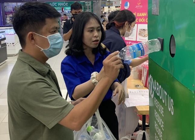 Đặng Nhật Uyên (sinh viên năm 4, Trường Đại học Nha Trang) hướng dẫn người dân sử dụng máy thu gom rác trong chương trình “Hè xanh mát, tích rác nhận quà” Ảnh: THỤC HIỀN